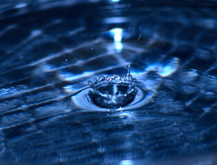 Ein Wassertropfen der auf die Wasseroberfläche prallt 