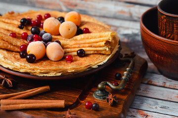 Fototapeta premium Golden pancakes with frozen fruits, decor and honey in a rustic style