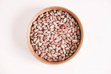 Raw dry beans in a wooden bowl on a white background. Top view. Copy, empty space for text