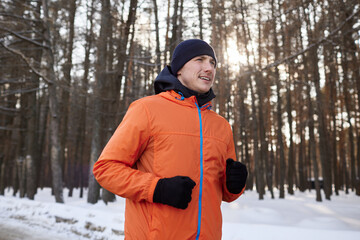 Fototapeta na wymiar Portrait of a man in bright sports clothes running through a winter forest