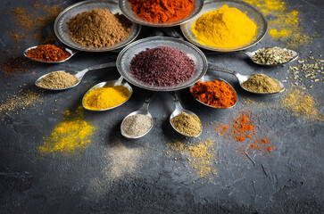 Assortment of natural spices on a vintage silver spoons or dishes on dark rustic stone background, Healthy spice concept