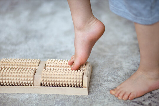 children's feet on a wooden roller massager, side view, close-up