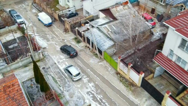 Aerial drone view of a residential distict in Chisinau, Moldova. Multiple buildings, road, moving car, Cloudy weather, bare trees, winter