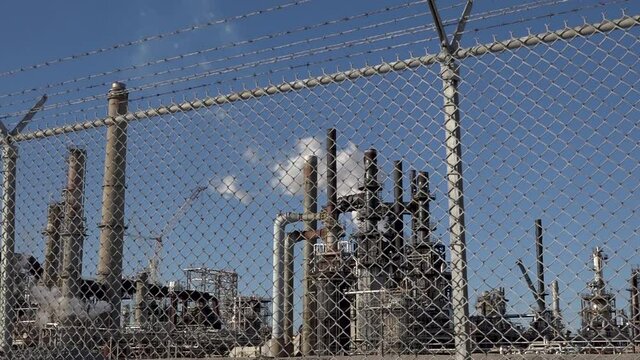 Industrial factory with smoke stacks protected by chain link fence, pollution, industry, polluting manufacturer, security, gas, oil, refinery, global warming, methane, carbon dioxide, private property