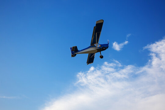 Small private plane climbs through the clouds. Fliyng ultralight aircraft across the blue sky. Copy space.