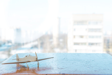 
a plastic model of a plane stands on a wooden shelf against the background of a window