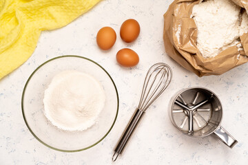 the process of making dough for pancakes with ingredients on a light table, eggs and flour are whipped with a mixer