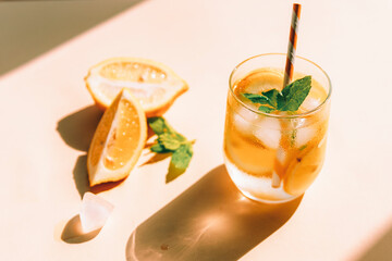 Fresh lemonade with mint leaves and ice cubes on yellow background, sharp shadows, top view