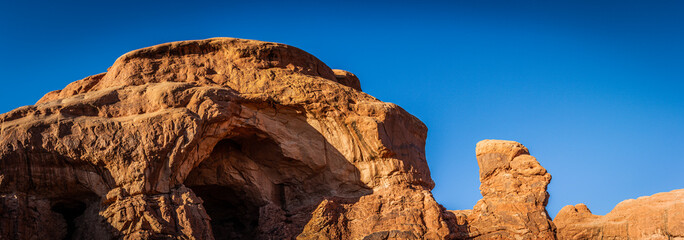 Red sandstone emerging arch with monolith agains blue sky in arches national park in Utha, America