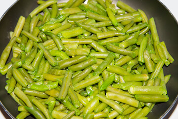 Delicious fresh green beans on a frying pan. Vegan food preparation. Angular view.