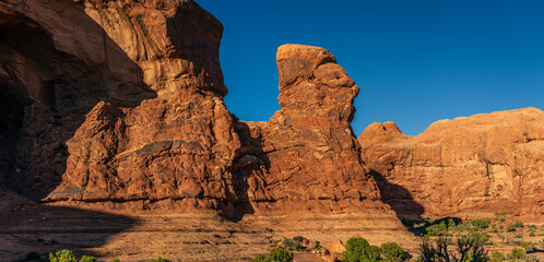 Wide shot of red sandstone moholith against blue sky at sunny day in Arches national park in Utah, America