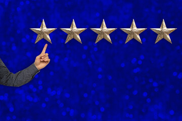 male client's hand shows five gold foil star on blue background, concept of evaluating the result, rating, Satisfaction