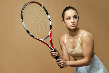 Pretty woman with tennis racket standing against yellow background