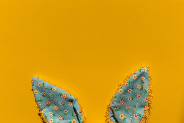 Ears of a toy easter bunny blue color on a bright yellow background and with an empty place for text