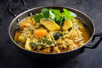 Traditional Indian sweet potato curry with eggplant served as top view in a design bowl
