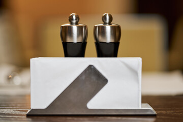 Salt and pepper grinders with napkins on set-up cafe table