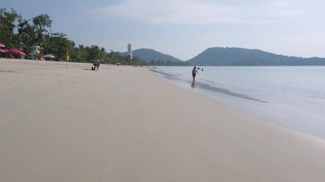 Panning view of the beach with white sand beach and clear blue sky in 50fps UHD 4k video. Patong beach at Phuket Thailand while without people in covid pandemic