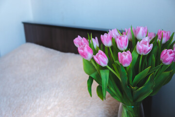 pink tulips in a vase on the background of the room