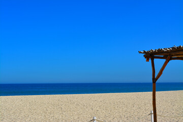 Estructura de madera y palma sobre la arena en playas de Los Cabos Mexico con un enorme cielo azul