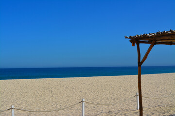 Estructura de madera y palma sobre la arena en playas de Los Cabos Mexico con un enorme cielo azul