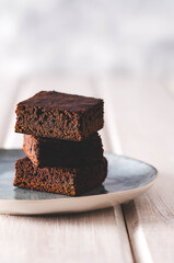 Brownies in a light blue dish on a white wooden backdrop. 