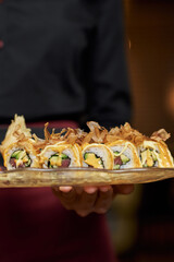 Waiter serving delicious set of avocado sushi