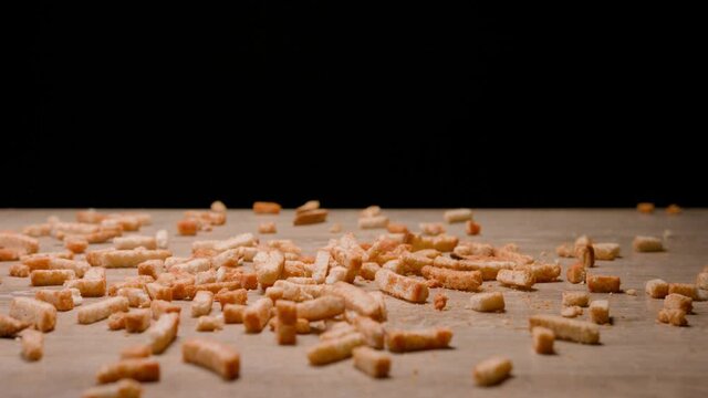 Salty breadstick crackers falling down wooden table on black background