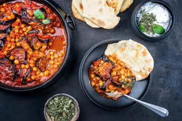 Modern style slow cooked Lebanese vegetarian eggplant stew maghmour served with chickpeas and pita bread as top view in a design pot
