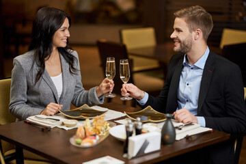 Charming man and beautiful woman cheering with glasses of champagne