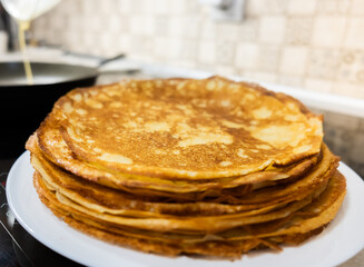 a stack of pancakes on a white plate on a kitchen background