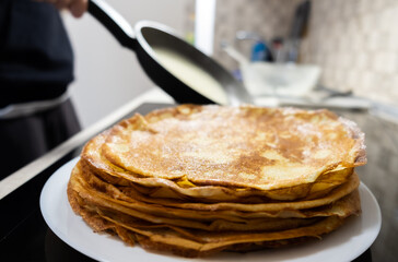 a stack of pancakes on a white plate on a kitchen background