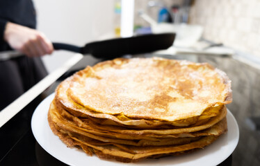 a stack of pancakes on a white plate on a kitchen background