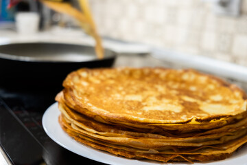 a stack of pancakes on a white plate on a kitchen background