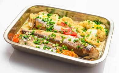 hake fish baked with vegetables close view, baking tray with tomatoes, broccoli and spices, home cooking