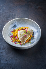 Modern style traditional sauteed skrei cod fish filet with skin in a bed of Persian jeweled saffron rice pilaw served in ceramic design bowl with copy space