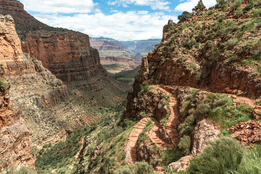 Epic, iconic and beautiful Grand Canyon hiking trail in Arizona, USA during summer time on a blue sky cloudy afternoon with huge cliff faces below. 