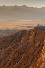 Fototapeta premium Lone hiker stand on a cliff overlooking the desert