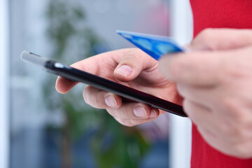 Hand enters credit card details in smartphone for purchase.