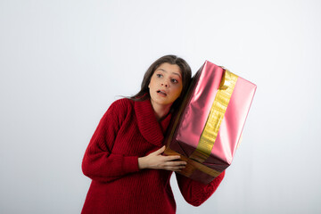Portrait of a young girl dressed in sweater and holding gift box
