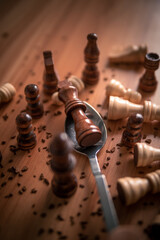 Chess pieces on a wooden table close up photo with king in a silver spoon victorious