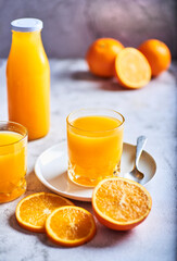 
orange juice in a glass container with some oranges