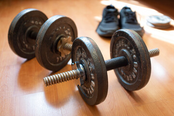 Obraz na płótnie Canvas Dumbbells padded from a pair of sneakers on a wooden floor