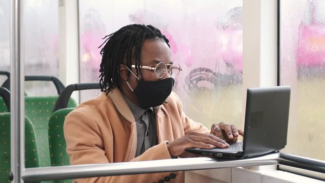 Public transport concept. Covid, coronavitus pandemic rules. An African man is going by gus to work wearing mask.