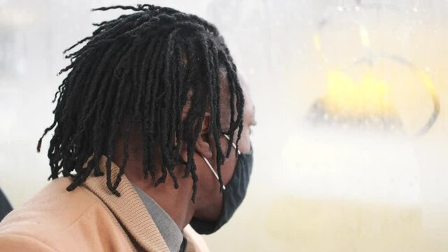 Public transport concept. Covid, coronavitus pandemic rules. An African man is going by gus to work wearing mask.