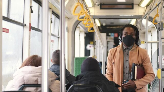 Public transport concept. Covid, coronavitus pandemic rules. An African man is going by gus to work wearing mask.