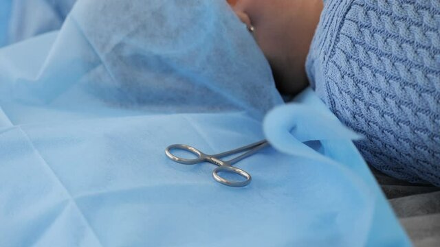 Preoperational period in operation theater patient getting ready for surgery on operating table. Some sterile medical instruments ready with surgical scissors gauze swabs in hospital operating room.