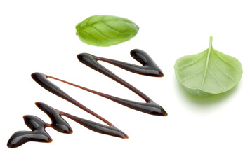 Balsamic vinegar cream and basil leaves isolated on white background. Italian salad dressing, sauce.