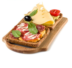 Open  faced sandwich canape or crostini on a wooden serving board  isolated on white background closeup.