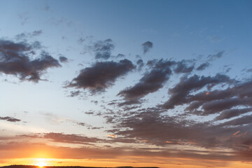 Sunset theme for sky replacement background with dark themed clouds, blue sky and sun shining on the horizon. Great for tranquil, calm, serene country or rural themed art.