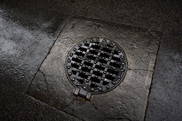 Sewer plate on a rainy and wet background street